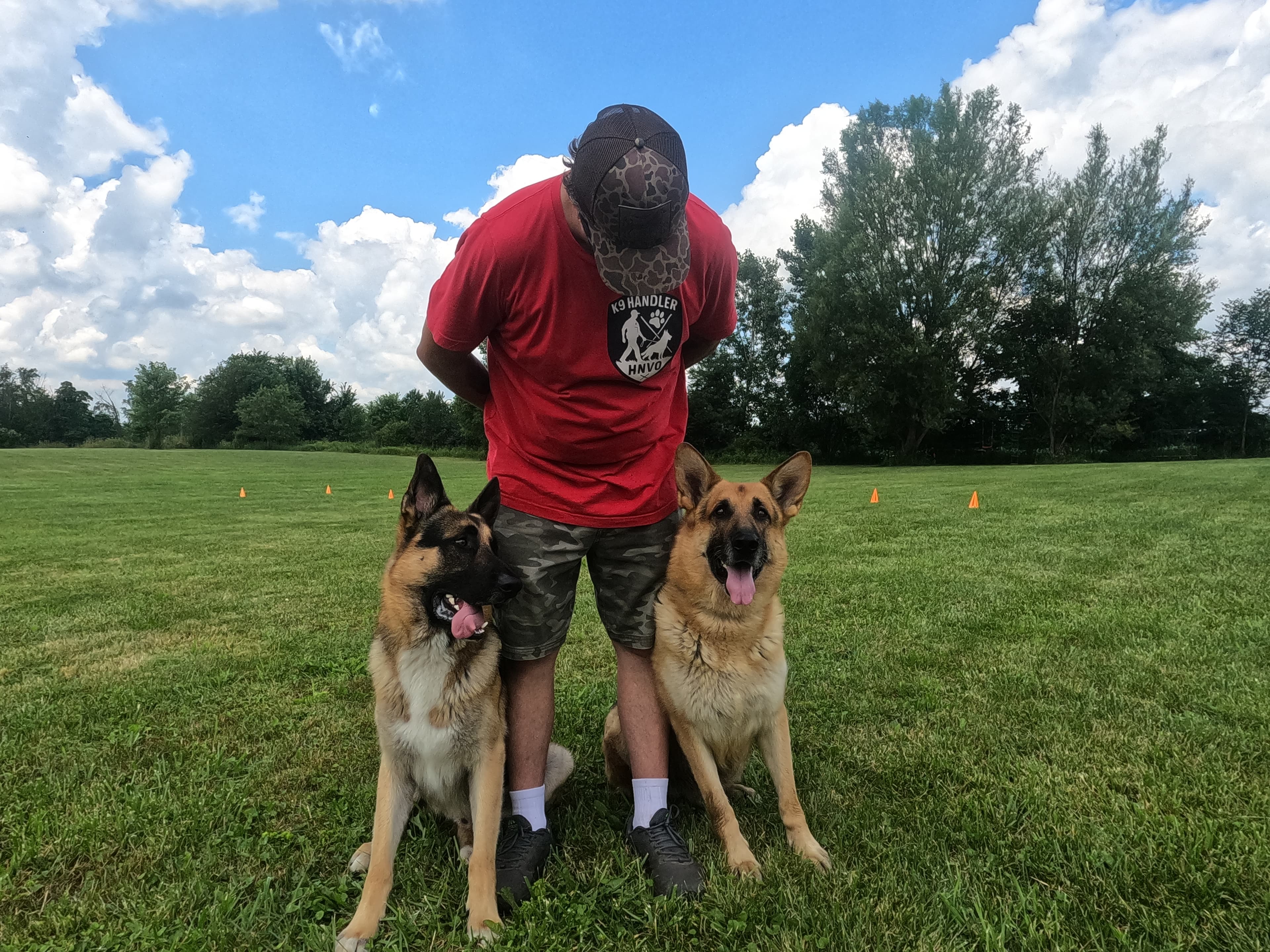Patriot K9 trainer working with two German Shepherds in the field.